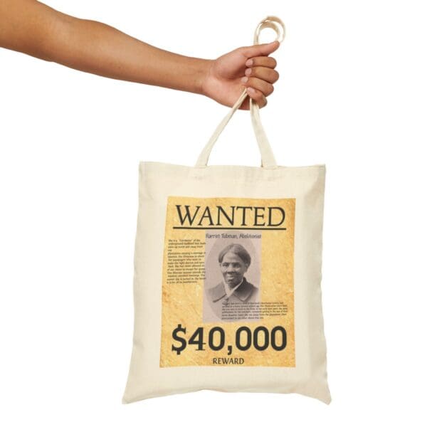 Hand holding a tote bag with a Harriet Tubman wanted poster.