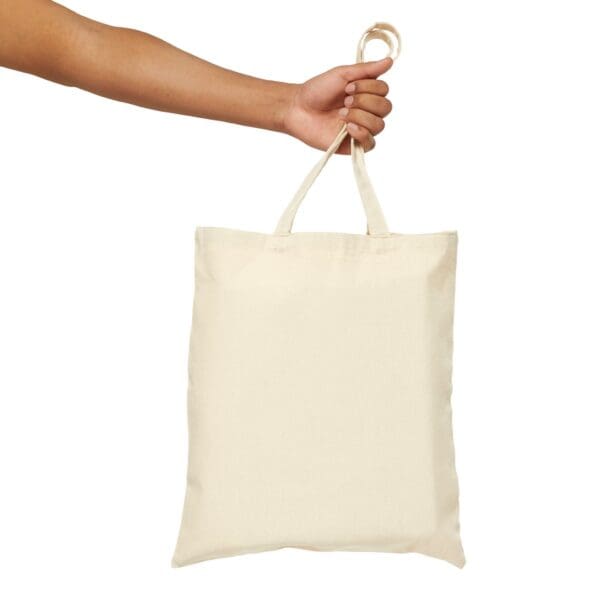 Hand holding a blank white tote bag.