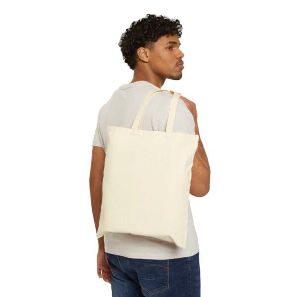 Man wearing a white t-shirt with a tote bag.