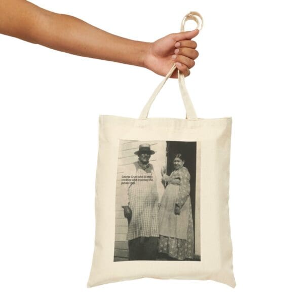 Hand holding a tote bag with George Crum on it.