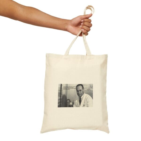 A hand holding a tote bag with a photo of a man.