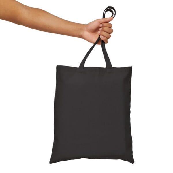 Person holding a black tote bag.