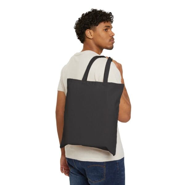 Man carrying black tote bag on shoulder.