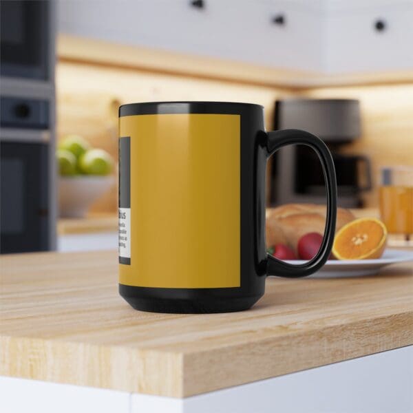 Black mug with yellow design on a table.