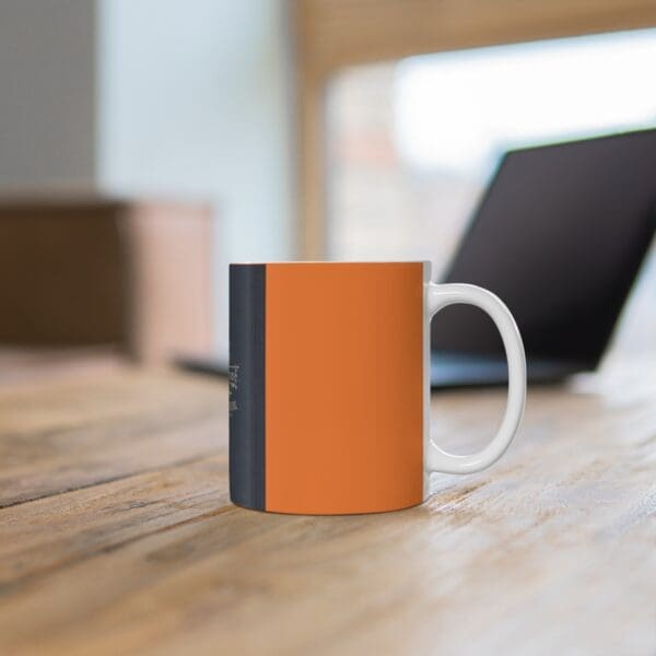 Orange and black mug on wooden table.