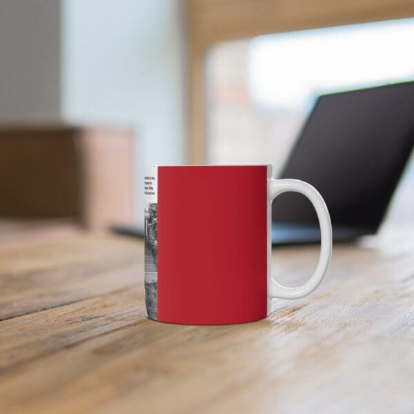 White mug with red design on wooden table.