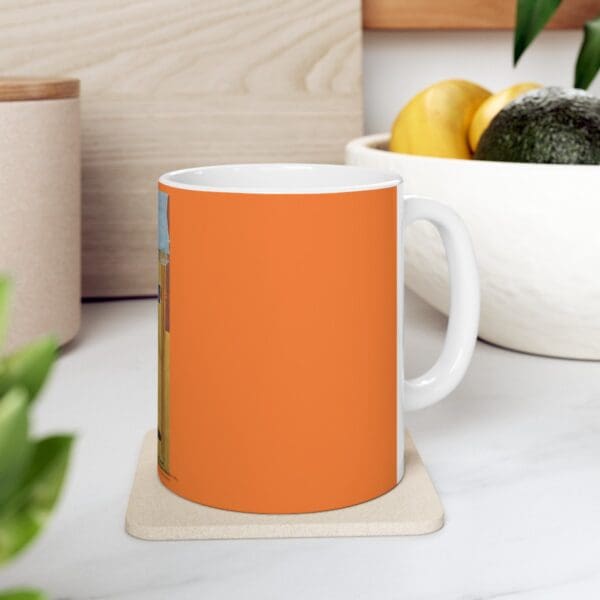 Orange mug with a white handle on a coaster.