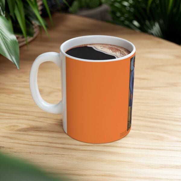 Orange coffee mug with a painting on it.