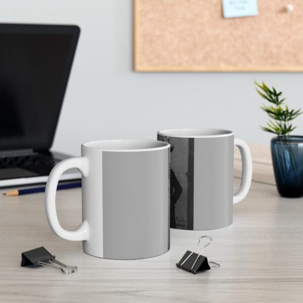 Two white coffee mugs with black and white images.