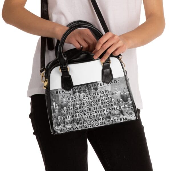 Black woman holding a Black Wall Street handbag.