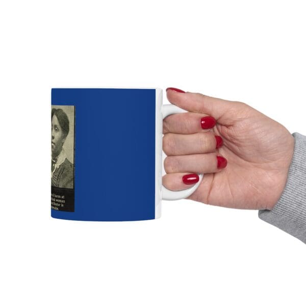 Hand holding a blue mug with a woman on it.