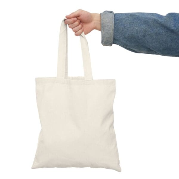 A hand holding a white tote bag.