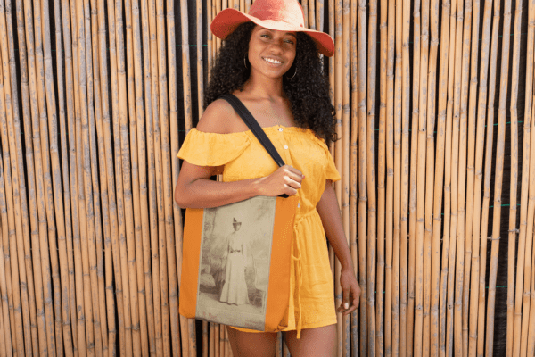 Woman in yellow dress holding tote bag.