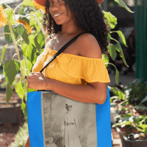 Woman in yellow dress carrying tote bag with portrait.