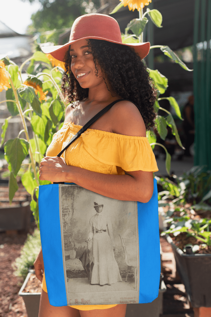 Woman in yellow dress carrying tote bag with portrait.