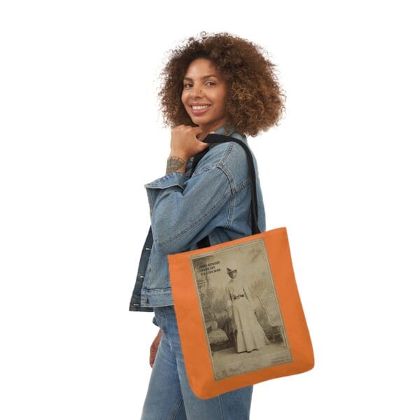 A woman holding an orange bag with a picture of a man.